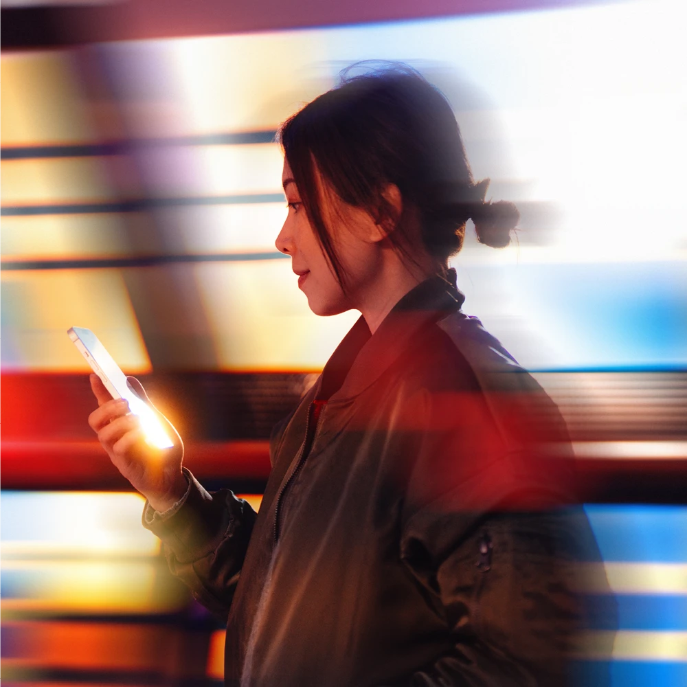 woman using her phone with a moving train behind her